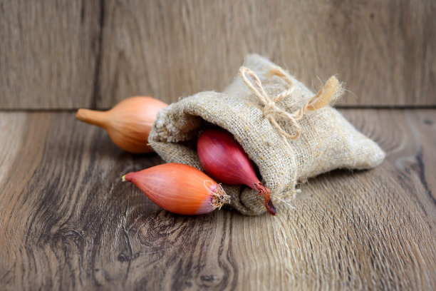 干洋葱球茎种植在一个小袋子，在木制的背景图片下载
