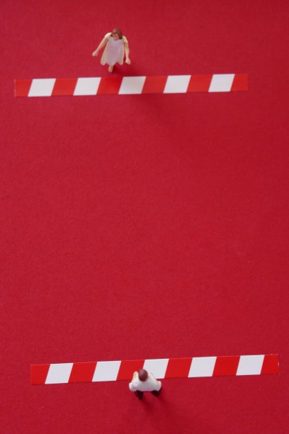 隔离检疫。社会距离。一个女孩的身影把她的手拉到一个男人的身影上，他们在红色的背景上分开条纹。保持距离的概念。冠状病毒图片下载