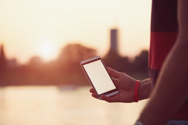 在河边拿着手机的男子。图片下载