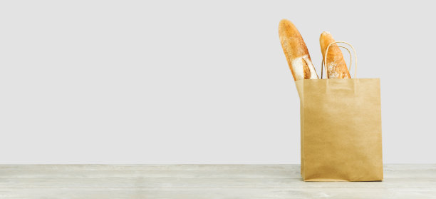 两块木头上的纸袋装的法式长棍面包图片下载