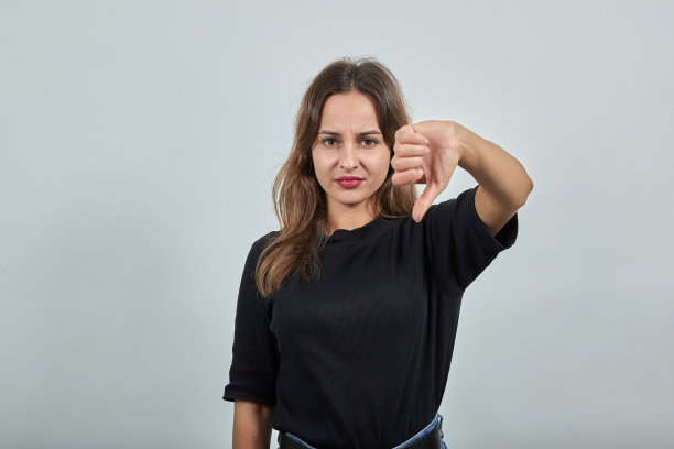 心情不好的沮丧女孩把她的拇指向下表示异议，反对图片下载