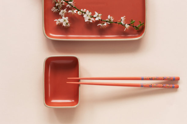 春天花的日本食物概念与盛开的樱桃树枝和服务筷子在珊瑚色蜡笔纸背景图片下载