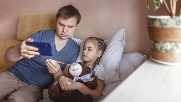 中年父亲看着智能手机屏幕，在家在线咨询医生，远程保健图片下载