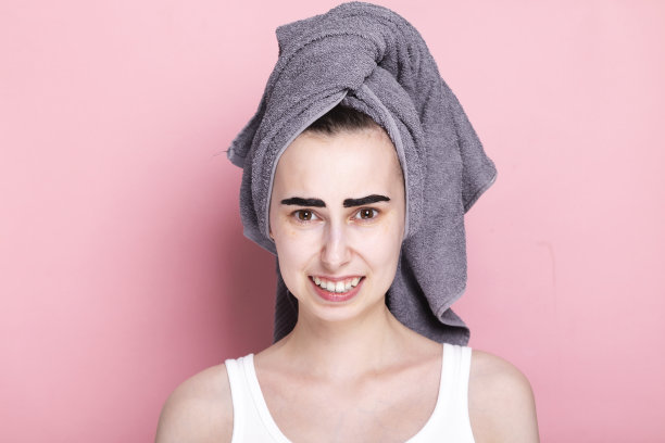 年轻女子头上裹着毛巾，自己画眉毛。感觉很尴尬，出了什么问题。居家和隔离的概念水疗日图片下载