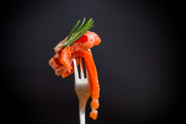 叉子上的红色咸鱼，黑色背景图片下载