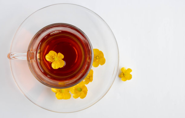 白色的背景上放着一只茶杯，茶杯上放着花茶和黄花。茶的概念，复古的风格。文本空间图片下载