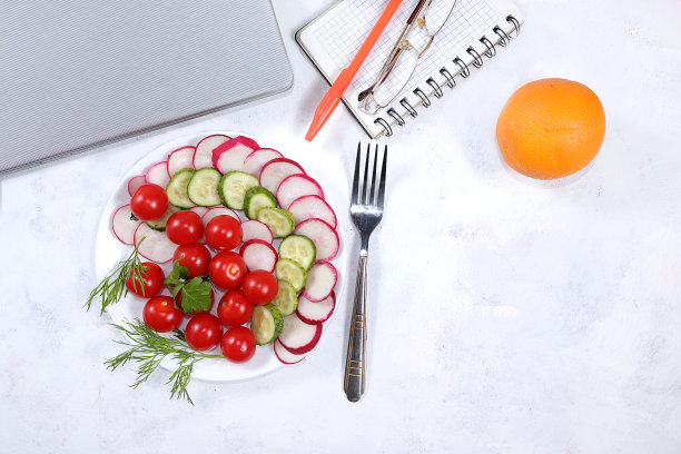 一个现代女性的桌面，家庭办公室。电脑，蔬菜沙拉，健康的生活方式。简约的商业理念，家的舒适，图片下载