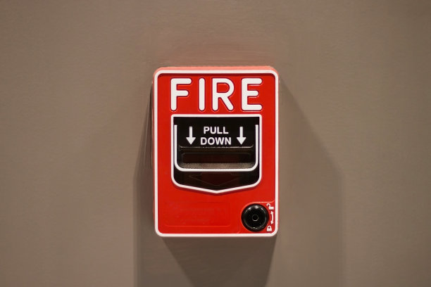 火灾报警按钮红色方盒风格贴在棕色房间的墙壁上，当发生火灾时，为建筑物内的人们的安全提供警示标志图片下载
