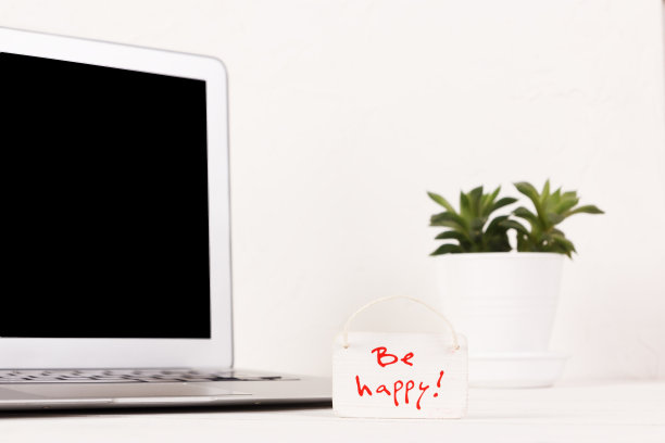 在笔记本电脑前的木制背景和白色墙壁上的激励标语。黑屏，拷贝空间。图片下载