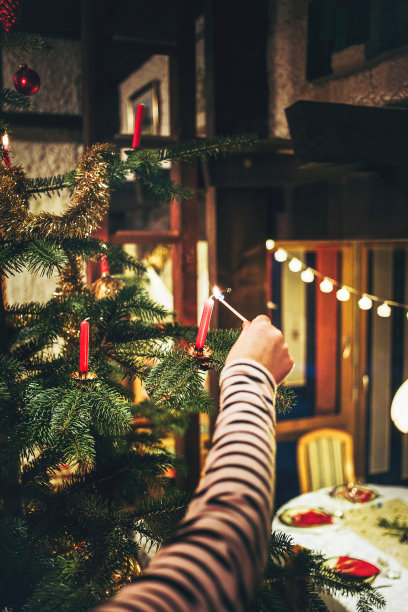 女孩们手在圣诞树上点燃蜡烛。图片下载
