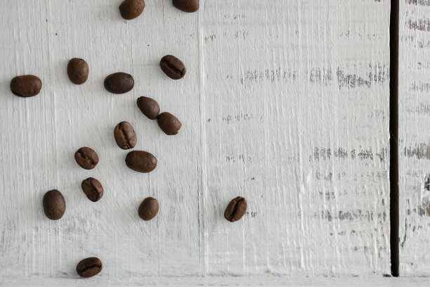 白色和棕色卡其色咖啡杯，热杯，深色烘焙咖啡豆在白色的木制背景图片下载