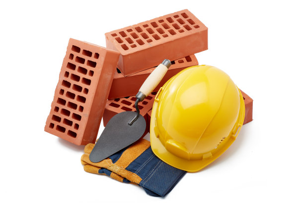 砖堆与砌体泥铲，施工安全帽和手套在白色背景。建筑的概念。图片下载