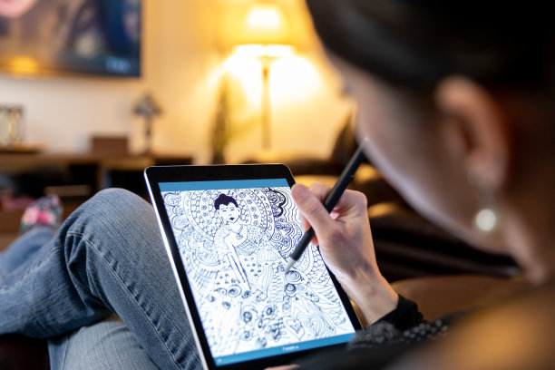 一个女人在起居室里用她的数字平板电脑画画图片下载