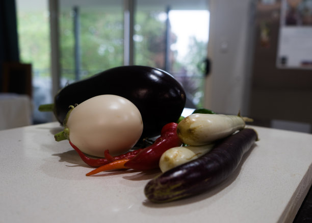 厨房长凳上的紫色和白色茄子和红辣椒的特写照片图片下载