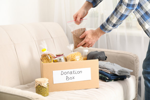 年轻人把食品放进捐款箱。志愿者图片下载