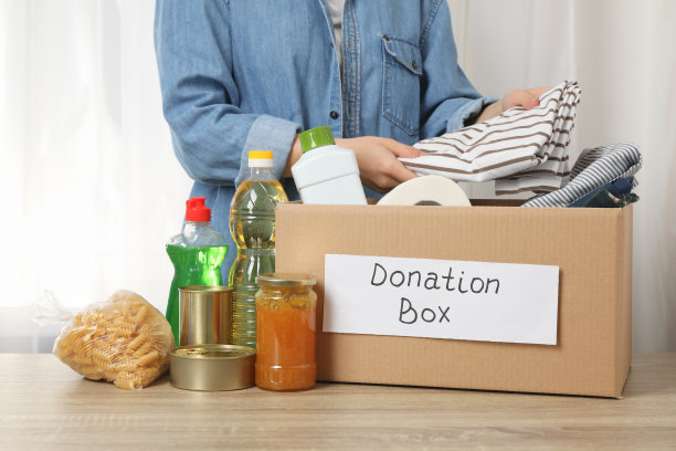 女人把衣服放进捐赠箱放在木桌上图片下载