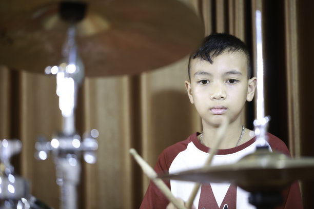 一个亚洲男孩在音乐教室里练习打鼓图片下载