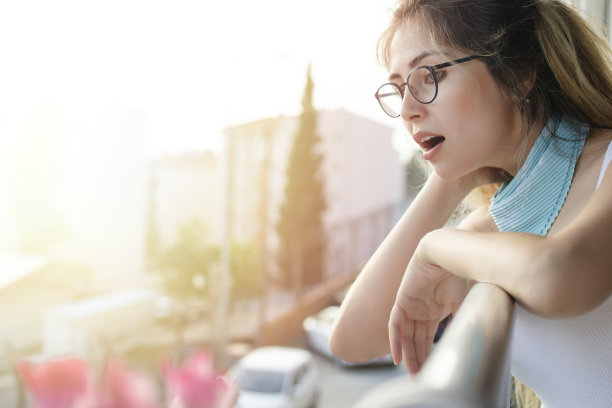 困惑的年轻女子在阳台上向外看图片下载
