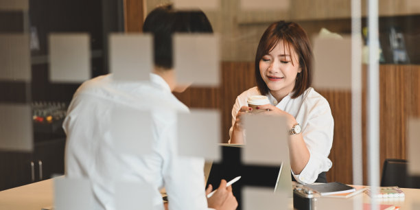 这是一对年轻夫妇用电脑和平板电脑工作的照片，他们一起坐在现代舒适的客厅的工作桌旁。图片下载