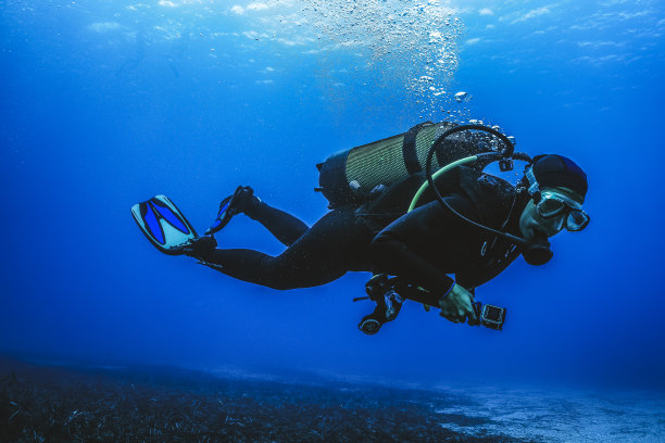 戴水肺的潜水员探索水下的礁石图片下载