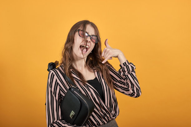 快乐的女孩微笑着，把拇指和小拇指放在脸旁边，像手机一样图片下载