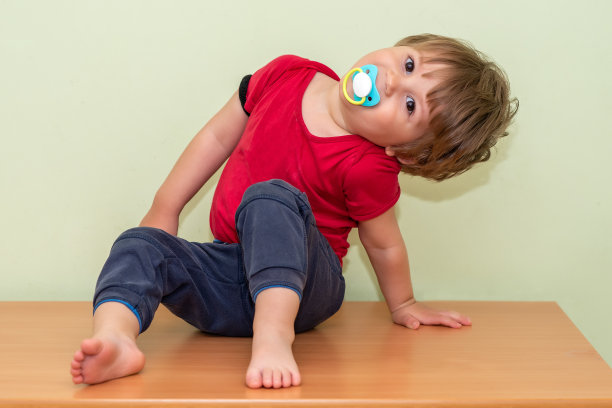 一个拿着奶嘴坐在衣柜里的男孩图片下载