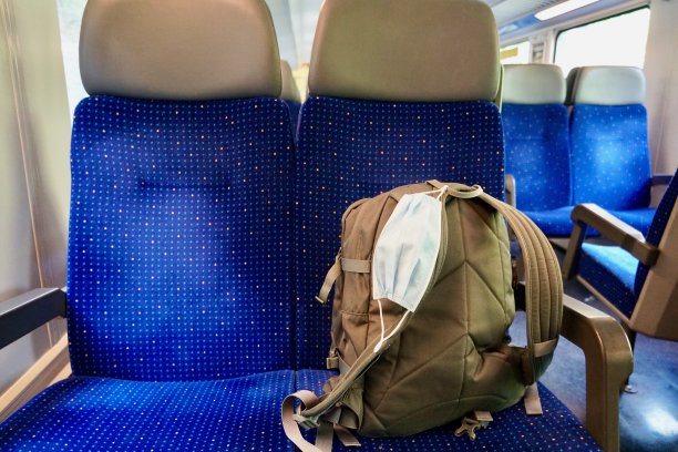 一个装在空车厢里的背包，上面有一个N95口罩，以便在需要时使用。在瑞士，在公共交通工具上，口罩不是强制性的。图片下载