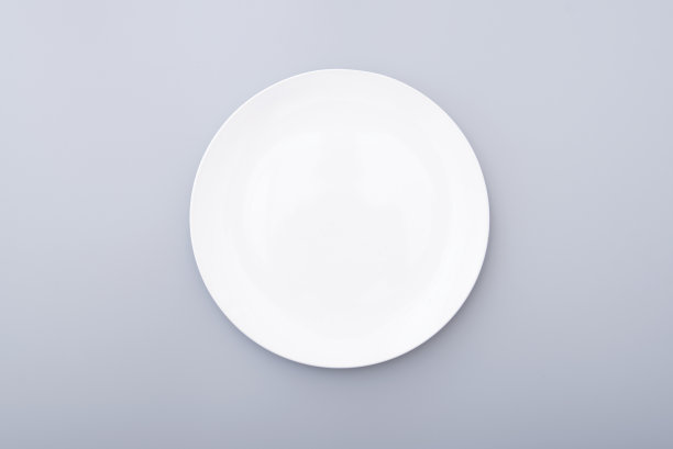 白色陶瓷板在灰色的桌子上，顶视图白色的盘子。圆形盘子,碗里。图片下载