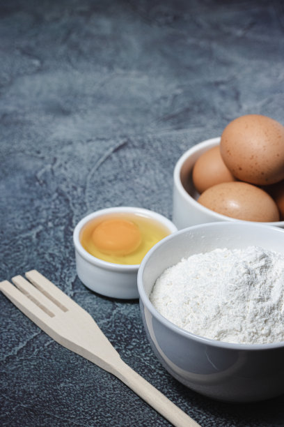 在有纹理的蓝色背景上准备蛋糕的材料和器具。鸡蛋，面粉，肉桂，牛奶。前视图。副本的空间。图片下载