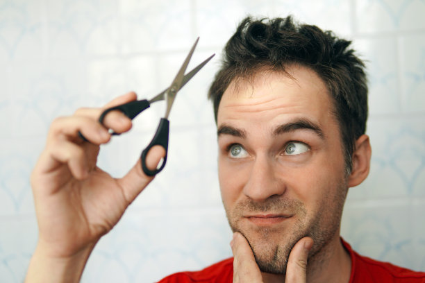 一名年轻人在隔离期间用剪刀剪自己的头发。害怕剪头发。自己把自己弄干净。图片下载