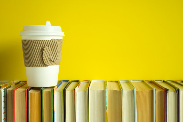一排整齐的书和一杯一次性咖啡图片下载