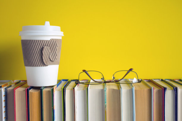 一排整齐的书和一杯一次性咖啡图片下载