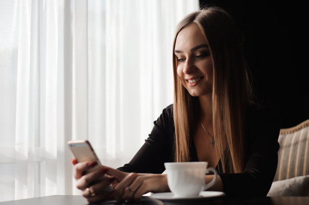 肖像年轻的女商人使用手机，而坐在舒适的咖啡店在工作休息图片下载