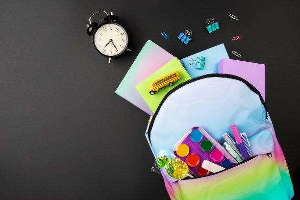 蓝色背包与明亮的颜色梯度与书籍和学校物体在黑色背景顶视图图片下载