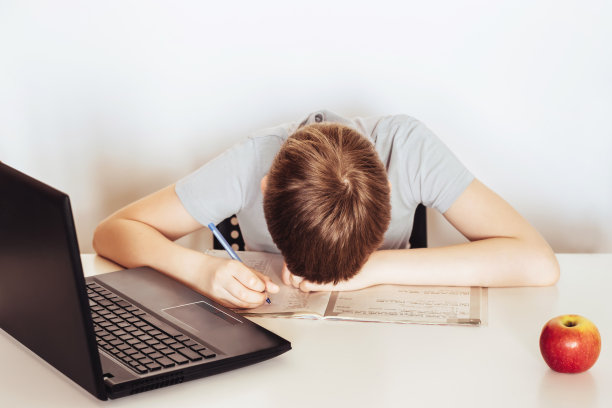 在家远程学习。累了不快乐的男生坐在电脑前学习。在线教育的概念。隔离期间的社会距离图片下载