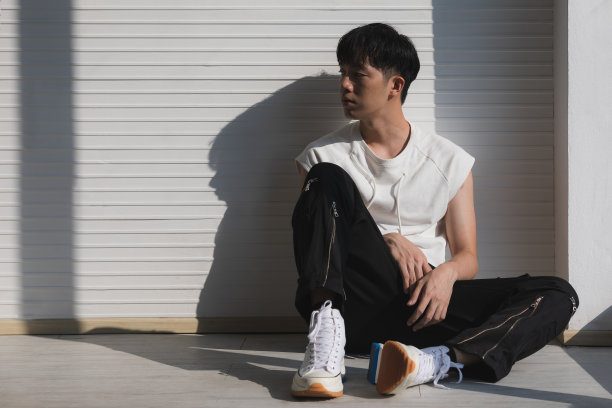 性感的亚洲模特男人坐和面对左边。图片下载