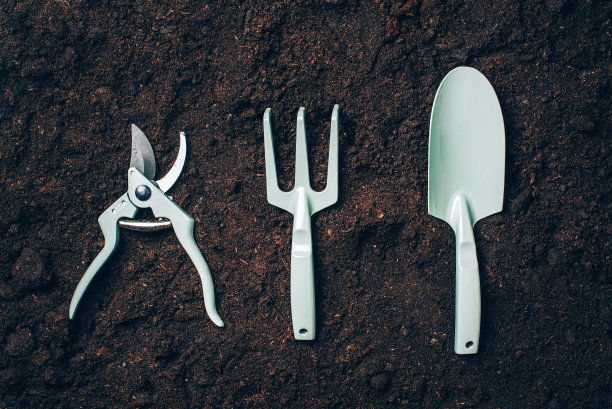 以土壤为背景的园艺工具和用具。顶部视图与复制空间。花园维护用的修枝机，耙子，铲子。夏天的季节。农业景观的概念图片下载