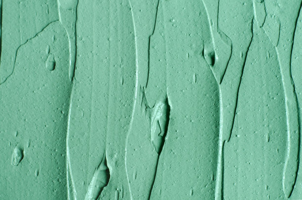 绿色化妆粘土(海带面膜、面霜、螺旋藻体贴)质地近距离，选择性聚焦。抽象的背景与画笔笔触。图片下载