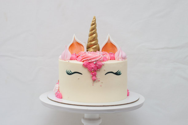 用生奶油装饰的独角兽分层蛋糕。浅灰色素色背景。图片下载