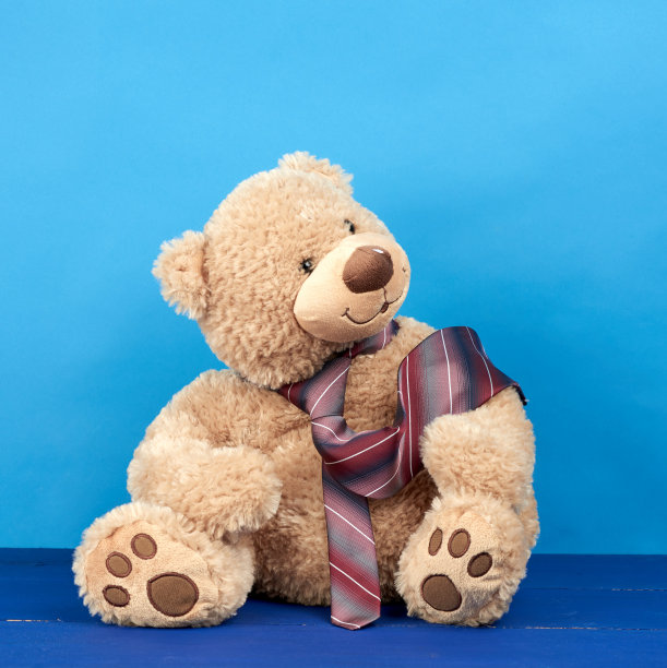 棕色的泰迪熊坐在蓝色的木制背景上图片下载
