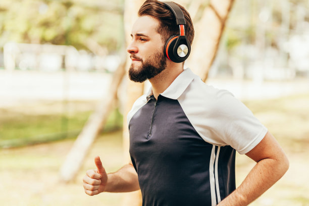 一个男人穿着运动服戴着耳机在公园里跑步图片下载