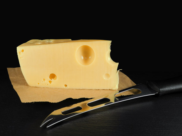 黑色背景上用特殊刀切的一块奶酪图片下载