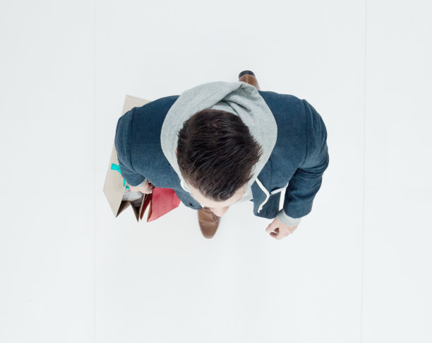 白人年轻男子购物狂穿着运动衫，拿着包走在白色背景前图片下载