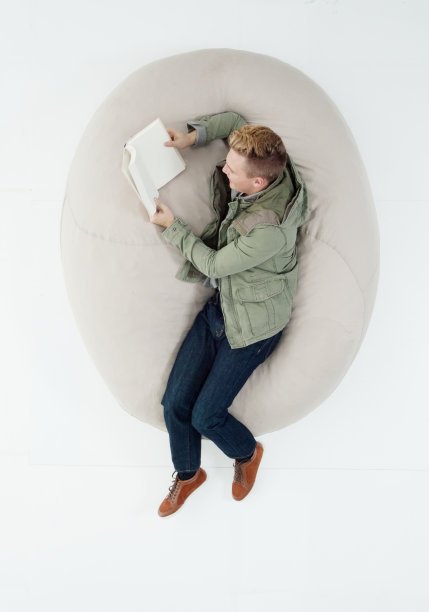 白人十几岁的男孩大学学生躺在前面的白色背景穿着牛仔裤和拿着教科书图片下载