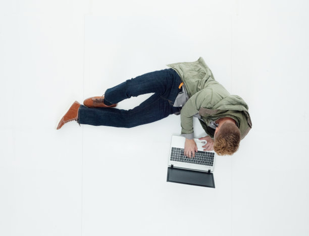 白人年轻男性穿着牛仔裤躺在白色背景下使用电脑图片下载