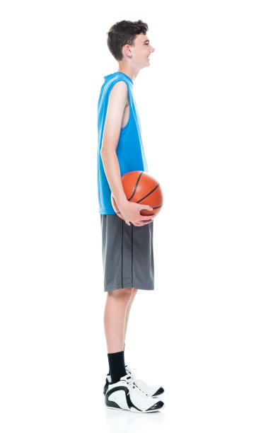白人少年篮球运动员站在前面的白色背景和拿篮球和使用运动球图片下载