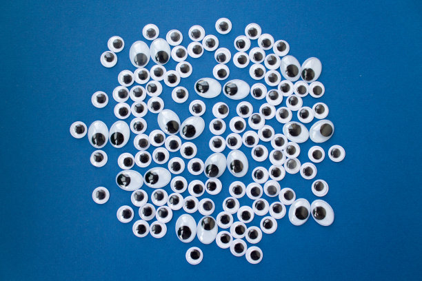 经典的蓝色背景上的谷歌玩具眼睛。个人数据安全、监视、间谍的概念。俯视图图片下载