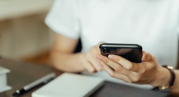 年轻女子手握智能手机，在社交网络上与朋友在桌子上聊天。图片下载