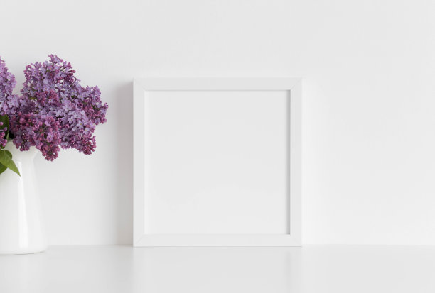 白色方形框架模型与一束丁香在花瓶上的白色桌子。图片下载