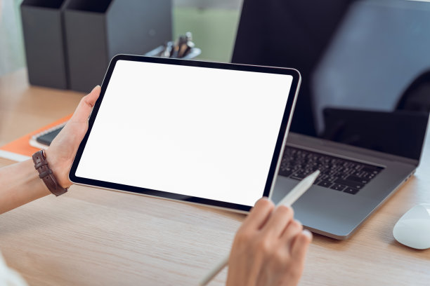 女人的手握着数字平板电脑的特写在桌子上，屏幕是空白的。图片下载